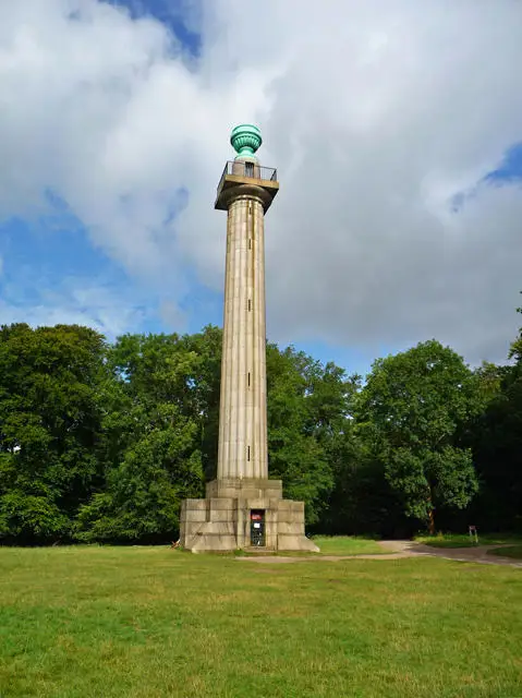 The stone Bridgewater Monument standing above grass and trees beneath a cloudy sky.